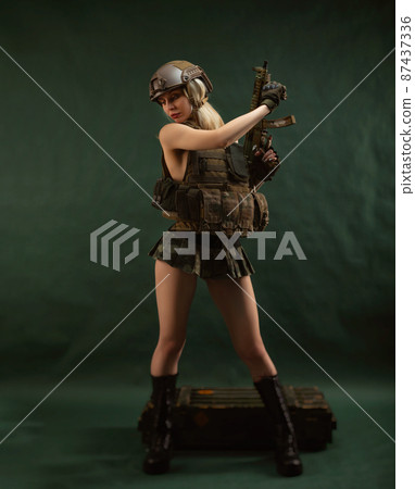 a girl soldier armed with an automatic rifle in military clothes on a green background a girl soldier armed with an automatic rifle in military clothes on a green background 87437336