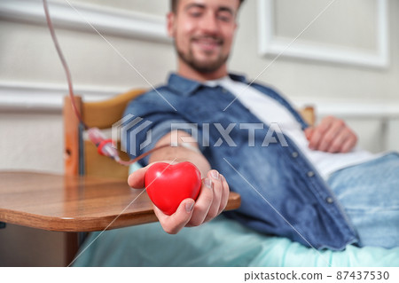Young man making blood donation in hospital, focus on hand Young man making blood donation in hospital, focus on hand 87437530