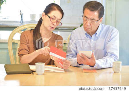 A wife holding a passbook, a husband hitting a calculator, and a senior couple receiving a pension to discuss how to manage their household budget. 87437649