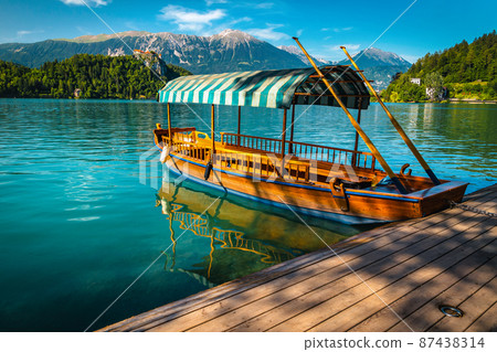 Anchored Pletna boat and castle in background, Bled, Slovenia 87438314