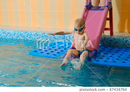 Toddler child learning to dive in indoor swimming pool with teacher. Boy kid sliding into water, balancing and general physical activity for kids in water, early development. Fun and action, splash 87438760