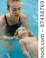 Toddler child learning to swim in indoor swimming pool with teacher. Floating in the water, balancing and general physical activity for kids, early development. Boy kid trained to kick legs and float 87438769