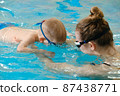 Toddler child learning to dive in indoor swimming pool with teacher. Standing on side, balancing and general physical activity for kids in water, early development. Boy kid instructed 87438771