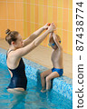 Toddler child learning to dive in indoor swimming pool with teacher. Standing on side, balancing and general physical activity for kids in water, early development. Boy kid instructed 87438774