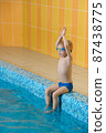 Toddler child learning to dive in indoor swimming pool with teacher. Standing on side, balancing and general physical activity for kids in water, early development. Boy kid instructed 87438775