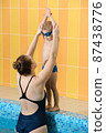 Toddler child learning to dive in indoor swimming pool with teacher. Standing on side, balancing and general physical activity for kids in water, early development. Boy kid instructed 87438776