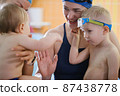 Kids communicating n indoor swimming pool with teacher. Happy time together and general physical activity for kids, early development. Boy kids early development  87438778