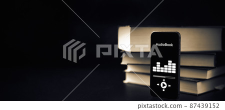 Audiobooks concept. Smartphone screen with audiobook application on paper books black background. Concept of education, library, students. Audiobooks concept. Smartphone screen with audiobook application on paper books black background. Concept of education, library, students. 87439152