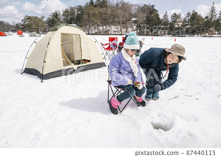 A girl fishing for smelt on the ice Winter camp 87440115