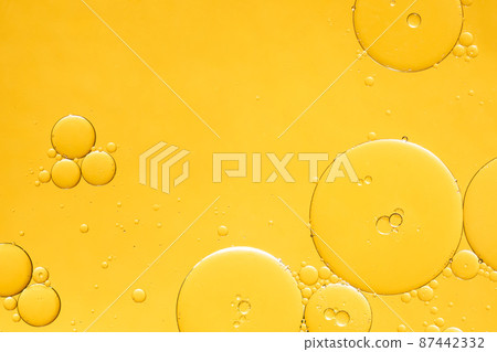 Golden yellow abstract oil bubbles or face serum background. Oil and water bubbles macro photography. 87442332