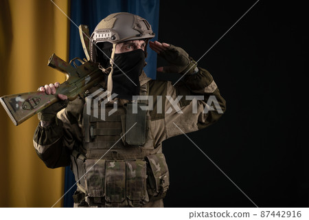 a male soldier in a military uniform and helmet with a weapon on the background of the national flag of Ukraine a male soldier in a military uniform and helmet with a weapon on the background of the national flag of Ukraine 87442916