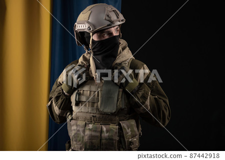 a male soldier in a military uniform and helmet on the background of the national flag of Ukraine a male soldier in a military uniform and helmet on the background of the national flag of Ukraine 87442918