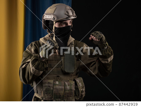 a male soldier in a military uniform and helmet on the background of the national flag of Ukraine a male soldier in a military uniform and helmet on the background of the national flag of Ukraine 87442919