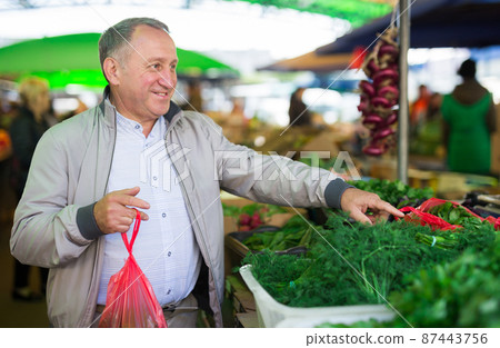 Man choosing vegetables in market Man choosing vegetables in market 87443756