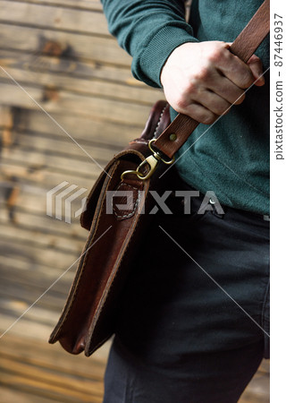 close-up photo of brown leather bag in mans hands 87446937