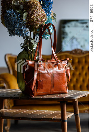 close-up photo of orange leather bag on a wooden table close-up photo of orange leather bag on a wooden table 87446998