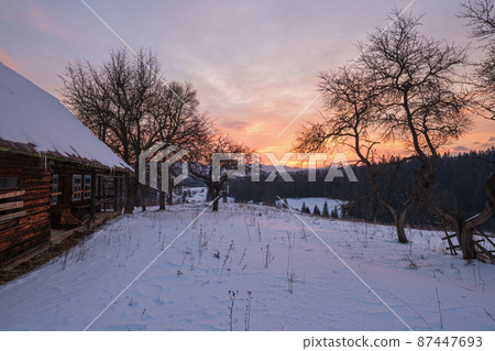 Small alpine village and winter snowy mountains in first sunrise sunlight around, Voronenko, Carpathian, Ukraine. 87447693