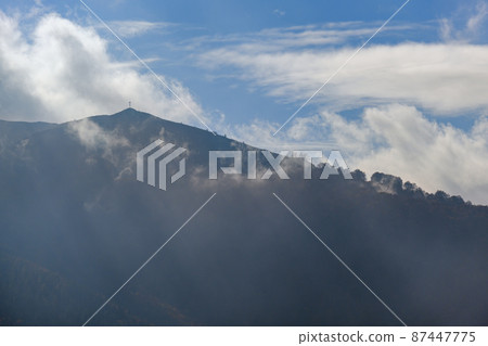 Morning foggy clouds in sunlight and autumn mountain countryside.  Ukraine, Carpathian Mountains, Borzhava Range, Transcarpathia. 87447775