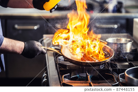 Detail of a flambe in a pan with flames reaching high 87448155