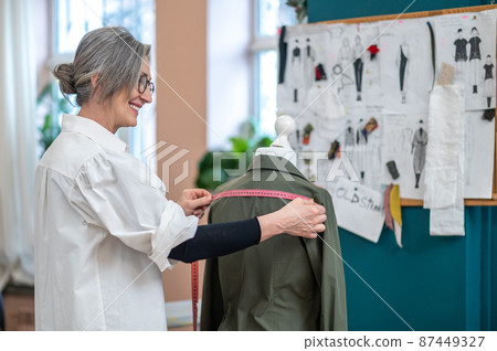 Profile of smiling woman with measure touching dummy 87449327