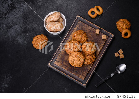 Tasty fresh oat cookies on a dark concrete background Tasty fresh oat cookies on a dark concrete background 87451135