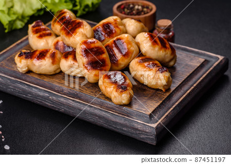 Grilled sausages with spices on a dark stone background Grilled sausages with spices on a dark stone background 87451197