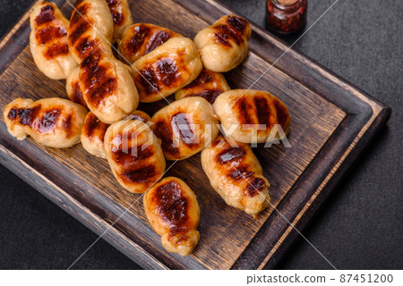 Grilled sausages with spices on a dark stone background Grilled sausages with spices on a dark stone background 87451200