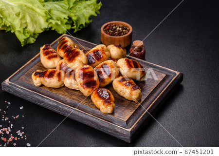 Grilled sausages with spices on a dark stone background Grilled sausages with spices on a dark stone background 87451201