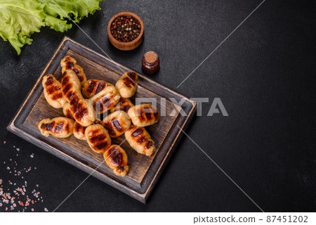 Grilled sausages with spices on a dark stone background Grilled sausages with spices on a dark stone background 87451202