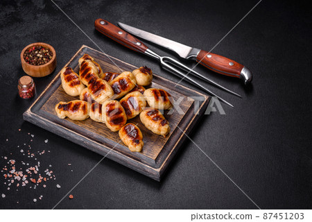 Grilled sausages with spices on a dark stone background Grilled sausages with spices on a dark stone background 87451203