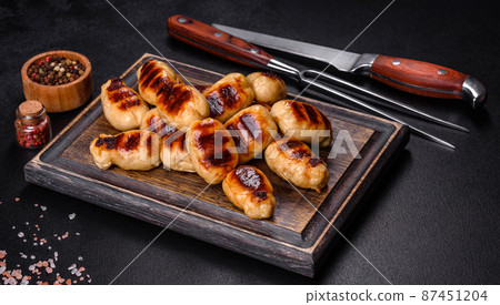 Grilled sausages with spices on a dark stone background Grilled sausages with spices on a dark stone background 87451204