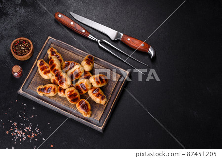 Grilled sausages with spices on a dark stone background Grilled sausages with spices on a dark stone background 87451205