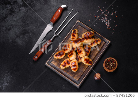 Grilled sausages with spices on a dark stone background Grilled sausages with spices on a dark stone background 87451206