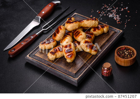Grilled sausages with spices on a dark stone background Grilled sausages with spices on a dark stone background 87451207
