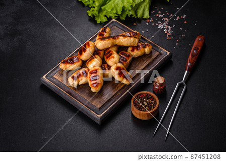 Grilled sausages with spices on a dark stone background Grilled sausages with spices on a dark stone background 87451208