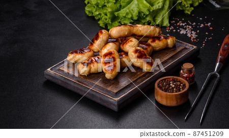 Grilled sausages with spices on a dark stone background Grilled sausages with spices on a dark stone background 87451209