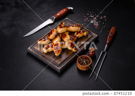 Grilled sausages with spices on a dark stone background 87451210