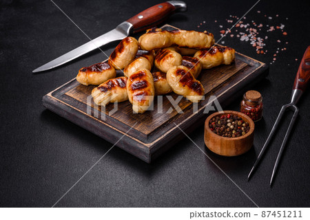 Grilled sausages with spices on a dark stone background Grilled sausages with spices on a dark stone background 87451211