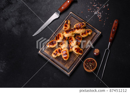Grilled sausages with spices on a dark stone background Grilled sausages with spices on a dark stone background 87451212