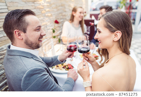 Men and women having a good time with food and drink in restaurant 87451275