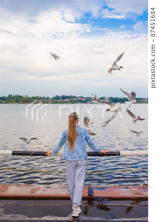 Cute little girl feed seagulls Cute little girl feed seagulls 87451684
