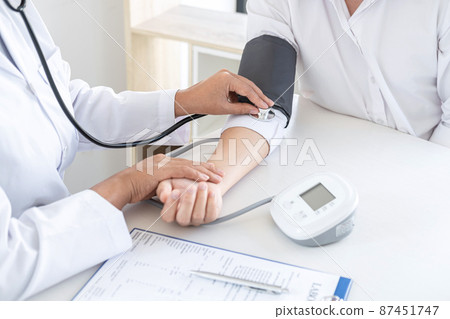 Doctor using a measuring blood pressure checking patient with examining, presenting results symptom and recommend treatment method, Healthcare and medical concept 87451747