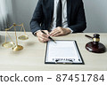 Counselor lawyer or notary working on a documents and report of the important case and wooden gavel, brass scale on table in courtroom 87451784