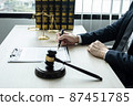 Counselor lawyer or notary working on a documents and report of the important case and wooden gavel, brass scale on table in courtroom 87451785