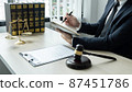 Counselor lawyer or notary working on a documents and report of the important case and wooden gavel, brass scale on table in courtroom 87451786