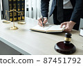 Counselor lawyer or notary working on a documents and report of the important case and wooden gavel, brass scale on table in courtroom 87451792