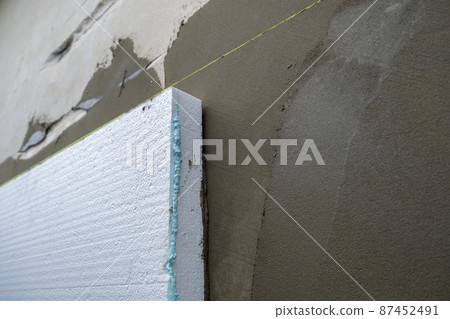 Installation of styrofoam insulation sheets on house facade wall for thermal protection. Installation of styrofoam insulation sheets on house facade wall for thermal protection. 87452491