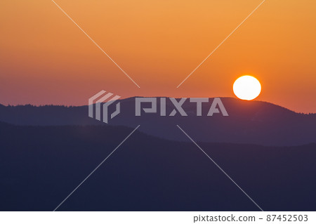 Fantastic wide panorama view of big bright white sun in dramatic orange sky over dark purple mountain range at sunset or sunrise in Carpathian mountains. Beauty and magnificence of nature concept. Fantastic wide panorama view of big bright white sun in dramatic orange sky over dark purple mountain range at sunset or sunrise in Carpathian mountains. Beauty and magnificence of nature concept. 87452503
