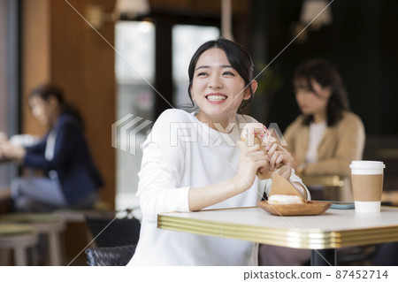 在咖啡館吃甜甜圈的年輕女人 87452714