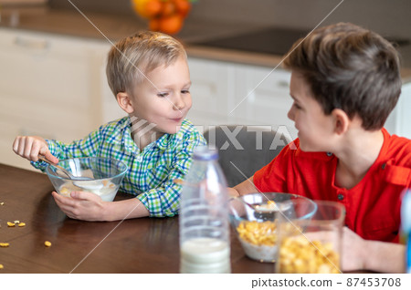 Two Caucasian kids eating cereals for breakfast Two Caucasian kids eating cereals for breakfast 87453708
